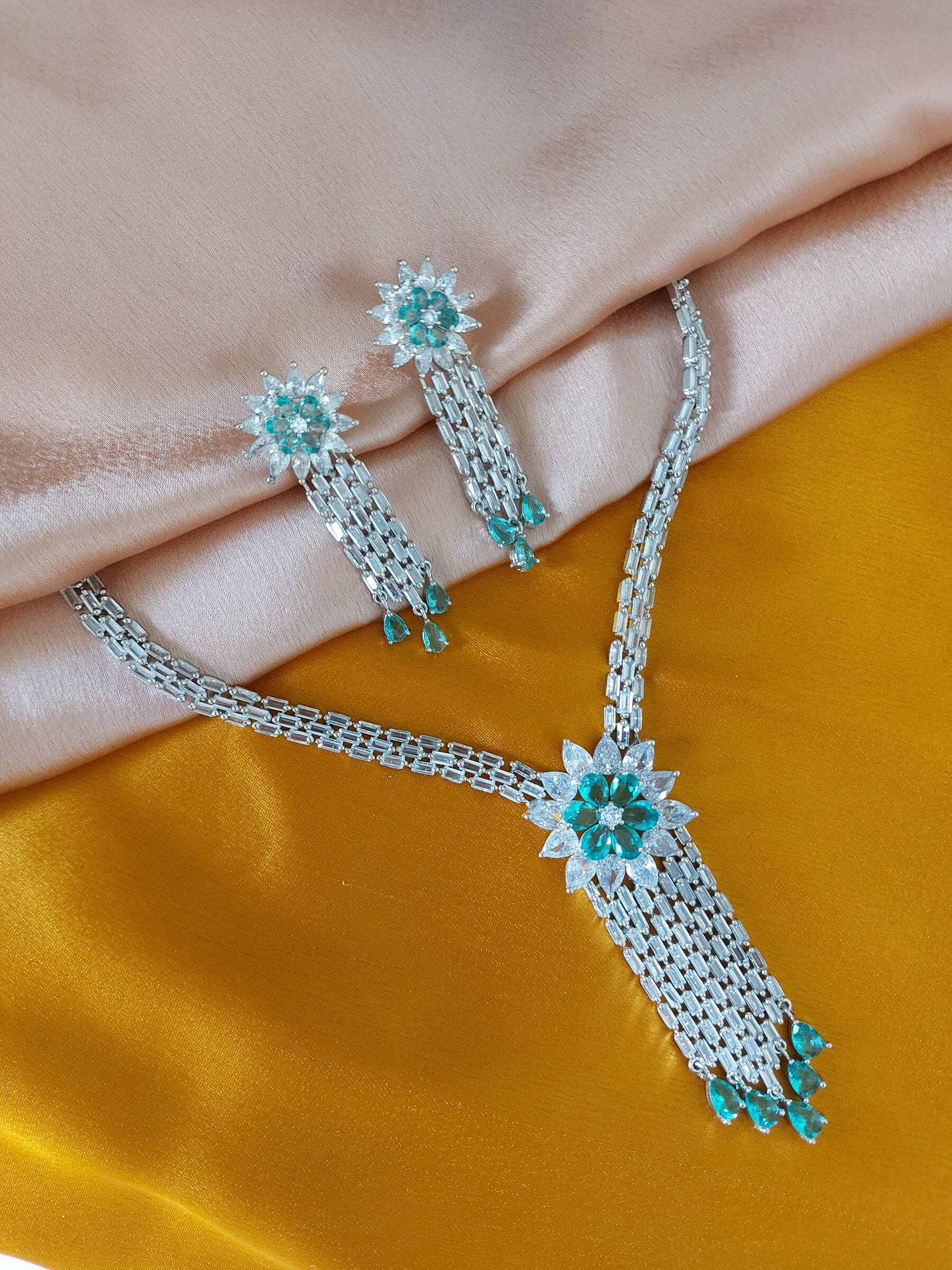 Megan Party Wear V Shaped Firoza Coloured American Diamond Necklace Set With Earrings